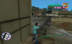 Tommy Vercetti about to shoot a man in black attire on the roof of the Cherry Popper Ice Cream Factory.