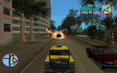 Tommy Vercetti driving his Kaufman Cabs taxi with the VIP passenger whilst the rival Vice City Cabs taxi explodes in the background.